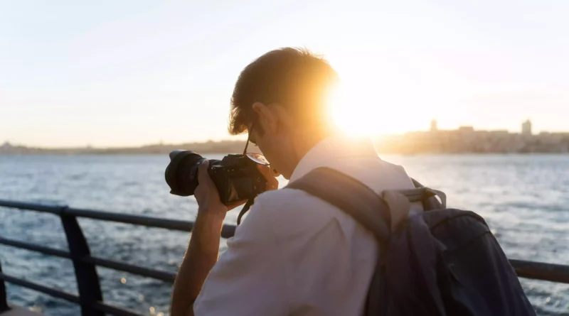 moço de mochila tirando foto em ponte de frente para o mar em intercâmbio de inglês nos Estados Unidos