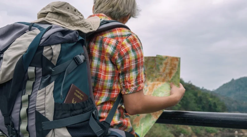 mochileiro segurando mapa aberto enquanto observa paisagem ilustrando o seguro viagem anual