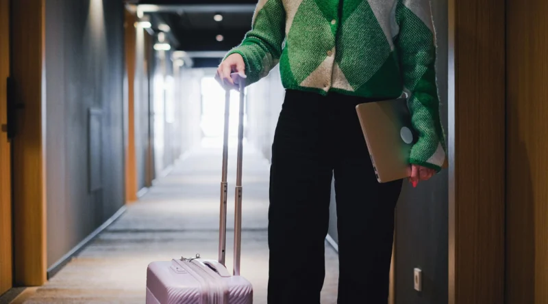 homem segurando a alça de uma mala de rodinhas em um corredor de hotel ilustrando preço de aluguel de malas